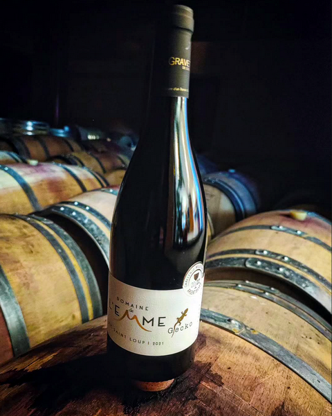 Bouteille L'Escale Gourmande des Vignerons de la Gravette, posée sur un fût